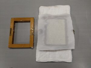 すいた紙の上にもう一枚のさらし布をかぶせる。

さらに板をのせて、両手でゆっくりおさえ水をきる