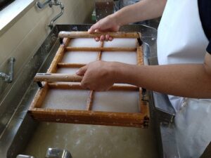 漉きごてを原料の中に静かに入れ、ゆすりながら紙を漉きあげます。